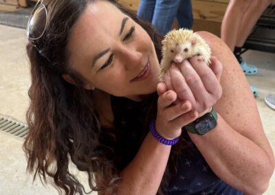 Woman holding a small hedgehog indoors.