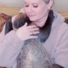 Woman cuddling a sloth on her lap.